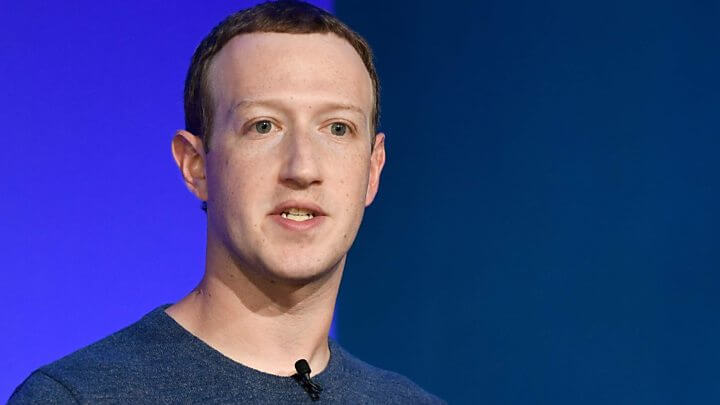 Mark Zuckerberg dengan kaos polos navy bluen dan mic clip on menempel di leher kaos